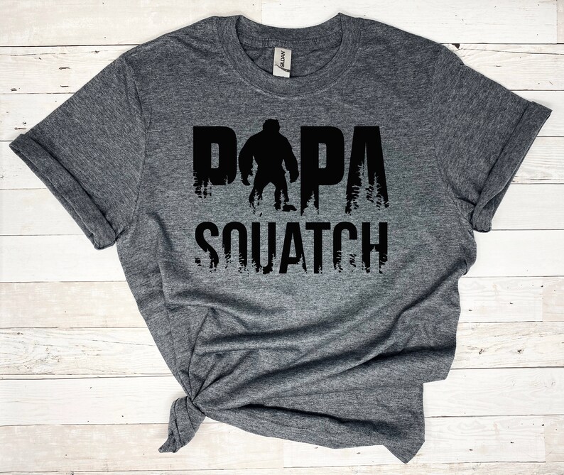 May include: Gray t-shirt with a black graphic of a Bigfoot with the text "Papa Squatch" printed on it.