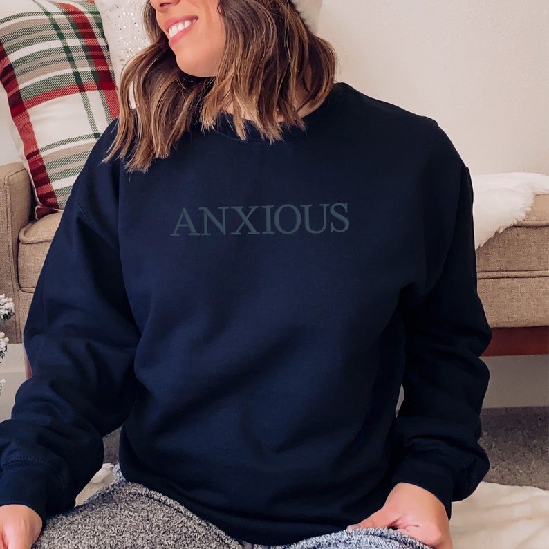 May include: A navy blue sweatshirt with the word "ANXIOUS" printed in white on the front.