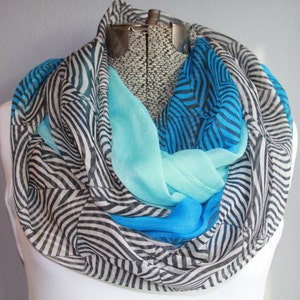 May include: A multi-colored infinity scarf with a zebra stripe pattern in black and white, and solid sections of turquoise and blue. The scarf is draped over a mannequin.