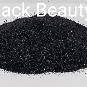 Peut inclure: Un tas de paillettes noires fines avec le texte "Black Beauty" en lettres blanches. Les paillettes semblent denses, avec une qualité légèrement réfléchissante, suggérant une finition métallique ou irisée. Le fond est blanc uni.