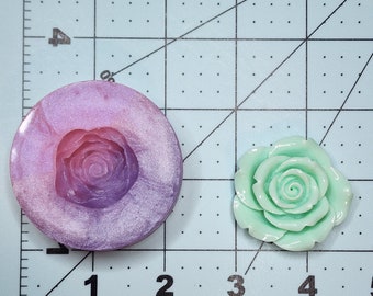 Può includere: Uno stampo in silicone per realizzare una decorazione per torte a forma di rosa, con un gradiente di colore viola chiaro e rosa, e una decorazione di rosa verde chiaro finita.