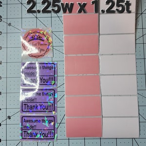 May include: A sheet of 2.25 inch wide by 1.25 inch tall pink and white labels. The labels are blank and ready to be used for a variety of purposes. There are three holographic stickers with the text "Awesome things inside!! Thank You!!!" on them.