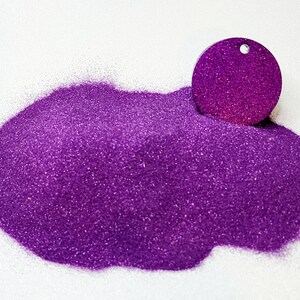 Puede incluir: Un montón de purpurina morada con una pequeña muestra redonda de purpurina en la parte superior.