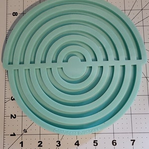 Può includere: Uno stampo in silicone blu chiaro con forma semicircolare e più cerchi concentrici. Lo stampo è progettato per creare oggetti in resina.