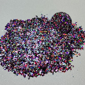 Op de afbeelding: Een hoop kleurrijke, iriserende glitter met een kleine bol van dezelfde glitter in het midden.