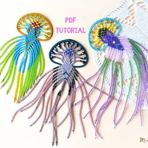 Op de afbeelding: Drie kralen-kwallen hangers met kleurrijke franjes. De hangers zijn gemaakt met verschillende kralen in tinten blauw, groen, paars en geel. De afbeelding bevat de tekst "PDF TUTORIAL".