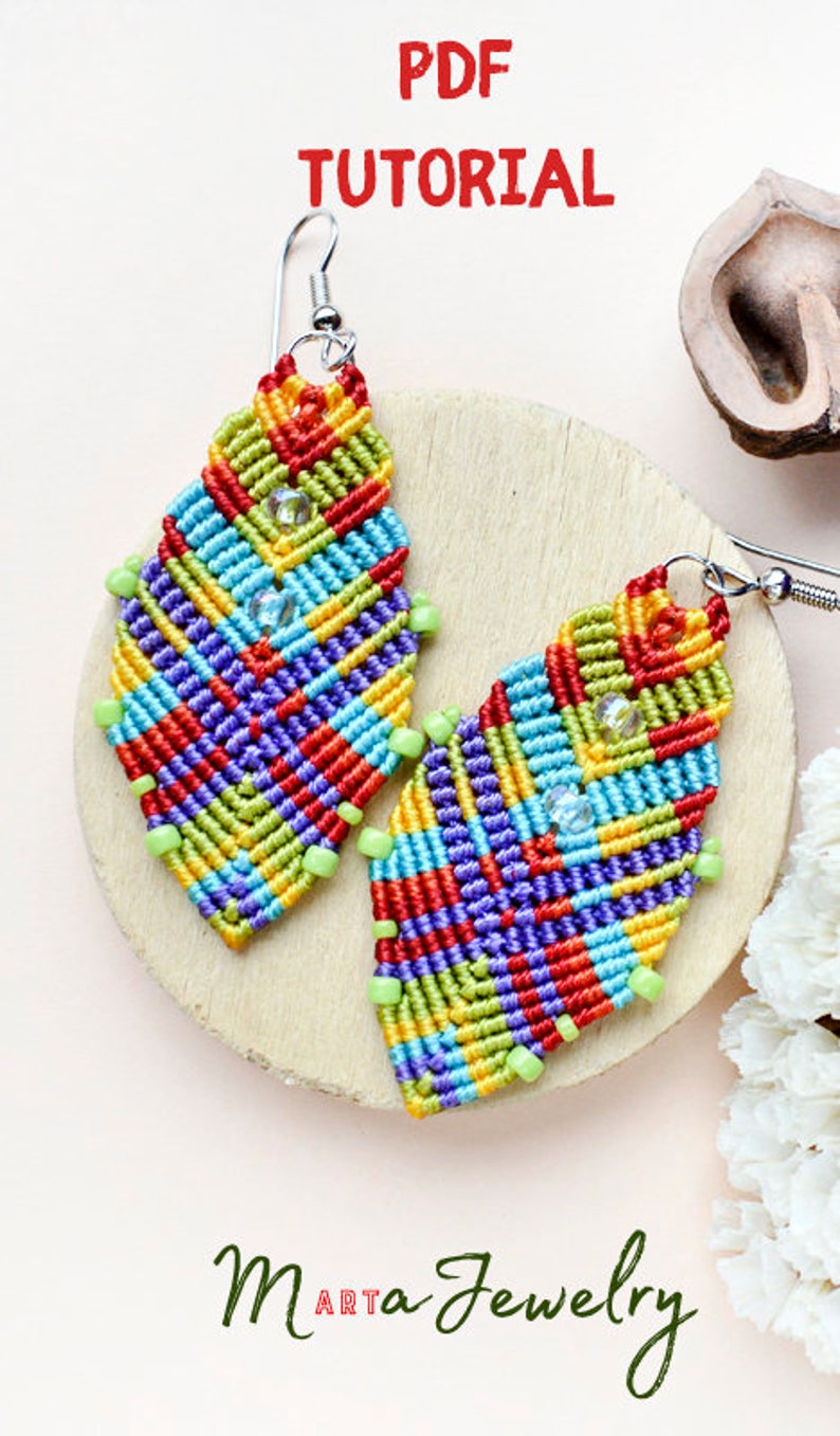 May include: A pair of colourful, geometrically patterned earrings made with macrame and beads. The earrings are in the shape of a teardrop and have a silver hook. The earrings are on a wooden surface with a white background. The text "PDF TUTORIAL" and "Maa Jewelry ART" are visible in the image.