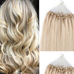 May include: A set of blonde human hair extensions with micro rings. The extensions are straight and have a natural blonde color. The extensions are shown in a net bag.