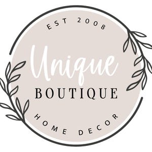 K&ouml;nnte beinhalten: Ein schwarz-wei&szlig;es Logo mit einem Kreis und floralen Akzenten. Der Text im Kreis lautet "EST 2008 Unique Boutique Home Decor".