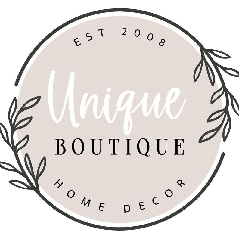 K&ouml;nnte beinhalten: Ein schwarz-wei&szlig;es Logo mit einem Kreis und floralen Akzenten. Der Text im Kreis lautet "EST 2008 Unique Boutique Home Decor".
