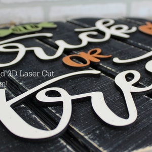 May include: A wooden sign with the words "Trick or Treat" in white raised lettering. The sign is painted black and has a distressed look. The words "or Treat" are in a cursive font. The words "Trick" are in a block font. The sign is decorated with a small pumpkin and a candy corn.