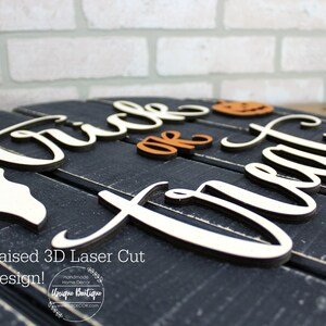 May include: A black wooden sign with the words "Trick or Treat" in white raised letters. The sign is decorated with a white ghost, an orange pumpkin, and a green candy.