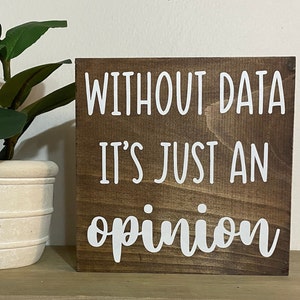 May include: A brown wooden sign with white text that reads "Without data it's just an opinion".