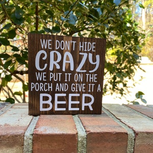 We don’t hide crazy we put it on the porch and give it a beer sign - backyard patio decor - funny family drinking quotes -