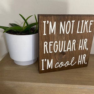Puede incluir: Un letrero de madera marr&oacute;n con texto blanco que dice "No soy como los RRHH normales, soy RRHH cool."