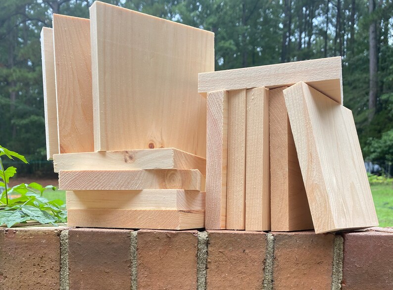 May include: A stack of unfinished wooden squares, some are stacked vertically and some are stacked horizontally. The wood is a light natural color.