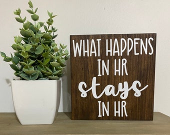 Puede incluir: Un letrero de madera marrón con texto blanco que dice "What happens in HR stays in HR".