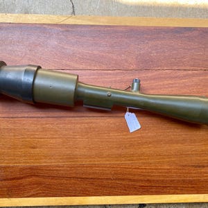 May include: A green metal scope with a black rubber eyepiece. The scope is about 18 inches long and has a small metal tag attached to it.