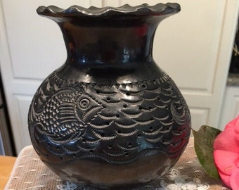 Jarrón negro tallado con diseño de peces y olas.