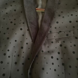 May include: A black blazer with a velvet collar and a black polka dot pattern.