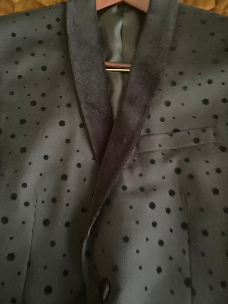 May include: A black blazer with a velvet collar and a black polka dot pattern.