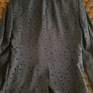 May include: A black blazer with a subtle polka dot pattern. The blazer has a velvet collar and a single button closure.