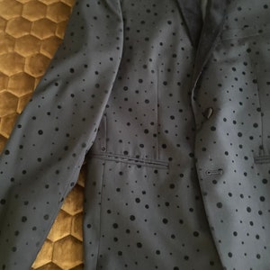 May include: A black blazer with a velvet collar and a black polka dot pattern.