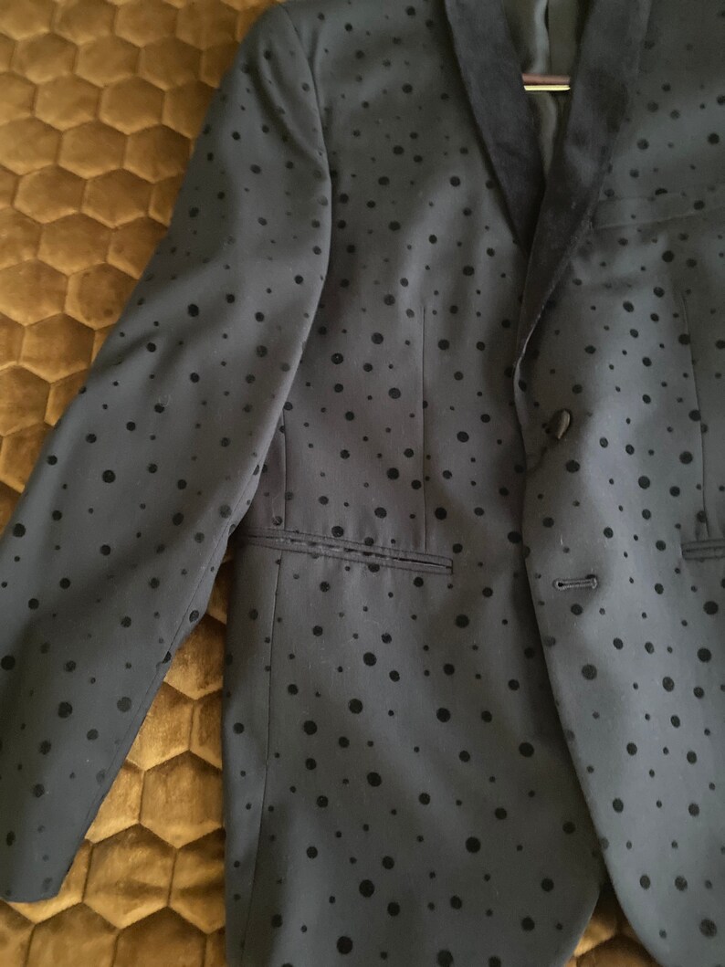 May include: A black blazer with a velvet collar and a black polka dot pattern.