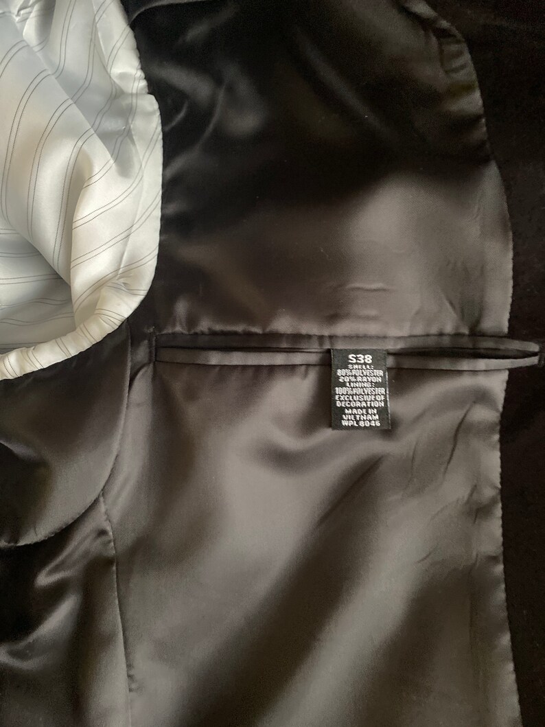 May include: A black blazer with a satin lining and a size tag that reads "$38", "SEA", "80% POLYESTER", "20% RAYON", "100% POLYESTER", "EXCLUSIVE OF DECORATION", "MADE IN VILTNAM", "WPL 8046".