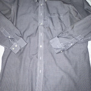 May include: A long-sleeve button-down shirt featuring a small-scale black and white checkered pattern. The shirt includes a pointed collar, a front button placket, a single chest pocket on the left side, and buttoned cuffs on each long sleeve.