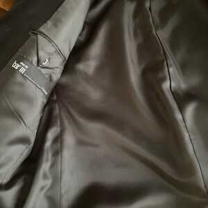 May include: The inside of a black blazer with a satin lining. The label reads "Bar III, Slim Fit, Exclusively for Macy's".