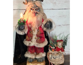 May include: A Krampus figure with curved horns, long fur, and a red coat with gold buttons, holding a lit candle and a metal chain. Beside it sits a small doll on a beige sack labeled Naughty, containing greenery and a red bow, with a small tag nearby.
