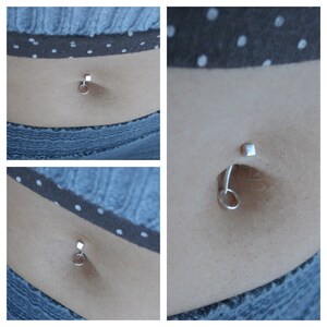 May include: Close-up of two different belly button piercings. The first piercing is a silver ring with a small silver cube on the top. The second piercing is a silver ring with a small silver cube on the top and a silver bar going through the cube.
