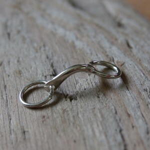 May include: A silver metal key chain with a curved design and a small ring.