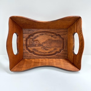 May include: A wooden serving tray with carved handles and a design of a farmhouse and wheat field with the text "Give Us This Day Our Daily Bread".