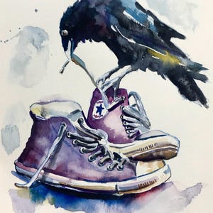Peut inclure: Peinture à l'aquarelle d'un corbeau noir perché sur une paire de baskets Converse violettes. Les ailes du corbeau sont déployées et son bec est ouvert comme s'il allait parler.