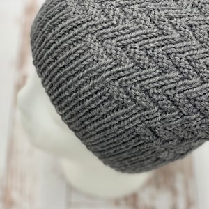 Puede incluir: Un gorro de punto gris con un patrón texturizado.