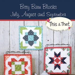 May include: Three small, colorful quilt blocks displayed on black metal stands. The blocks feature geometric patterns in shades of red, green, blue, and white. The text "Bitty Barn Blocks" and "July, August and September" are visible. A small white teapot is in the foreground.