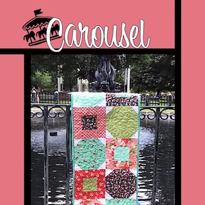 May include: A colorful patchwork table runner with a variety of geometric shapes and floral patterns in shades of pink, green, blue, and black. The runner is hanging on a black metal fence near a pond. The text "Tricia Lynn Maloney Orphan Quilt Designs For Villa Rosa Designs" is at the bottom of the image.