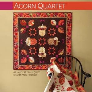 May include: A quilt pattern featuring an acorn motif. The pattern is called "Acorn Quartet" and is 41 inches by 41 inches. It is a lap/wall quilt and is charm pack-friendly.