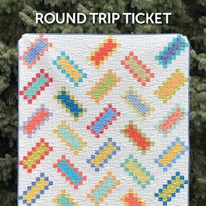 May include: A quilt pattern called "Round Trip Ticket" by Atkinson Designs. The quilt features a white background with colorful patchwork squares in shades of blue, red, yellow, and green. The pattern is designed to create a modern and geometric look.