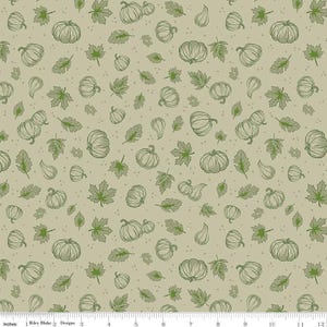 May include: A fabric pattern featuring a light beige background with a repeating print of dark green line-art pumpkins, gourds, and various leaves, accented by small dark green dots. A 12-inch ruler is visible along the bottom edge.