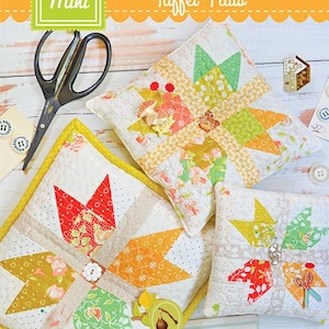 May include: Three mini quilted pillows with a starburst pattern in shades of green, yellow, orange, and red. The pillows are on a white wooden surface with buttons and scissors. The text "Mini Tuft Flats" is at the top of the image.