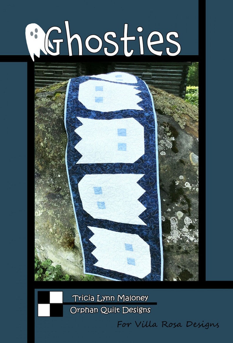 K&ouml;nnte beinhalten: Eine blaue und wei&szlig;e Steppdecke mit einem Muster aus Geistern. Die Steppdecke liegt auf einem mit Moos bewachsenen Stein und ist in der Mitte gefaltet. Die Steppdecke tr&auml;gt den Titel "Ghosties" und stammt von Tricia Lynn Maloney, Orphan Quilt Designs f&uuml;r Villa Rosa Designs.
