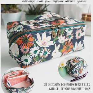May include: A rectangular fabric pouch with a dark blue background featuring a floral and white rabbit print. It has a teal zipper with two metal pulls and a top handle. The text reads SPRING ROLL POUCH and lists dimensions of 9 1/2"W x 4"H x 4"D.