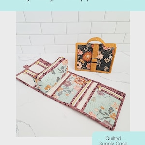 May include: A Nightingale Zipper Case, a quilted supply case pattern, is displayed. The case is open, revealing multiple zippered compartments with a floral pattern. A matching, closed case with a handle is also shown. The text "Nightingale Zipper Case" is at the top.