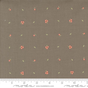 May include: A fabric with a brown background featuring a repeating pattern of small, light orange berries and green leaves. The fabric has a textured appearance and is marked with a ruler along the bottom edge.