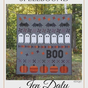 May include: A grey quilt titled SPELLBOUND by Jen Daly Quilts featuring rows of orange stars, black bats, white ghosts, and orange pumpkins. The word BOO is printed in black block letters. The quilt is displayed hanging outdoors on a line.