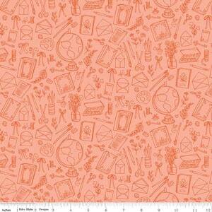 May include: Peach-colored fabric with a repeating pattern of stationery and travel-themed illustrations. The design includes globes, books, envelopes, scissors, paint palettes, and floral elements. The fabric is 12 inches wide.