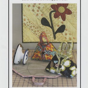May include: A sewing pattern titled Sisters' Common Thread Travel Iron Tote featuring a white mini iron and two fabric totes. One tote has a colorful abstract pattern, the other has a black, white, and green floral print on a flat ironing pad.